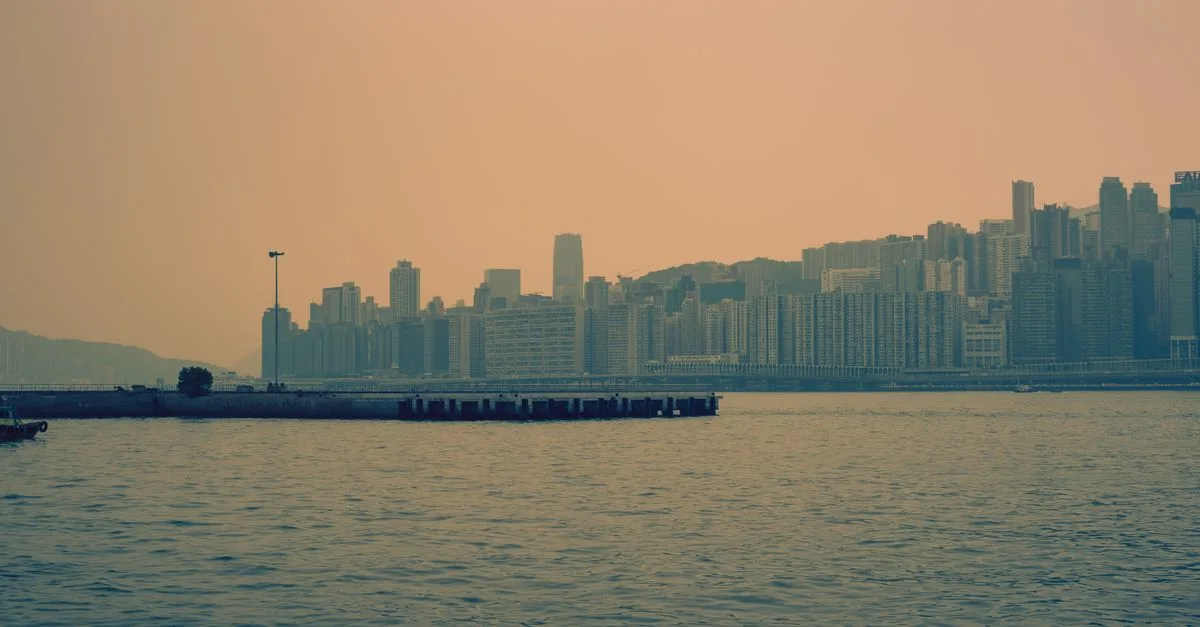 Kowloon skyline at dusk, overlooking Victoria Harbour with a muted urban vibe.