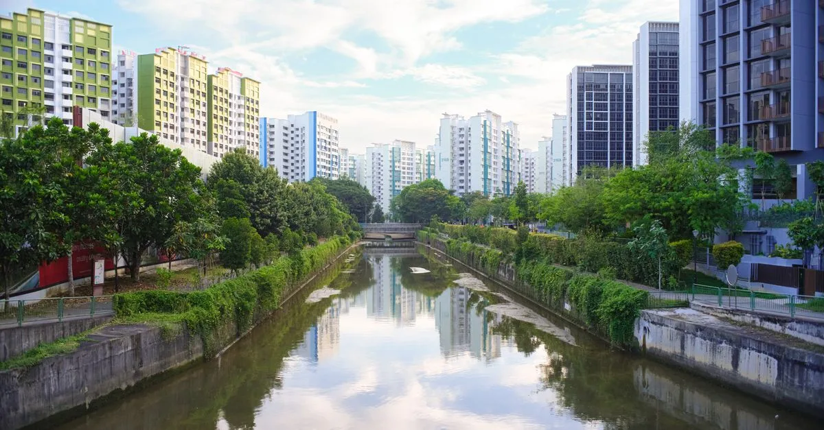 A scenic view of a river flanked by modern high-rise buildings and greenery in an urban setting.