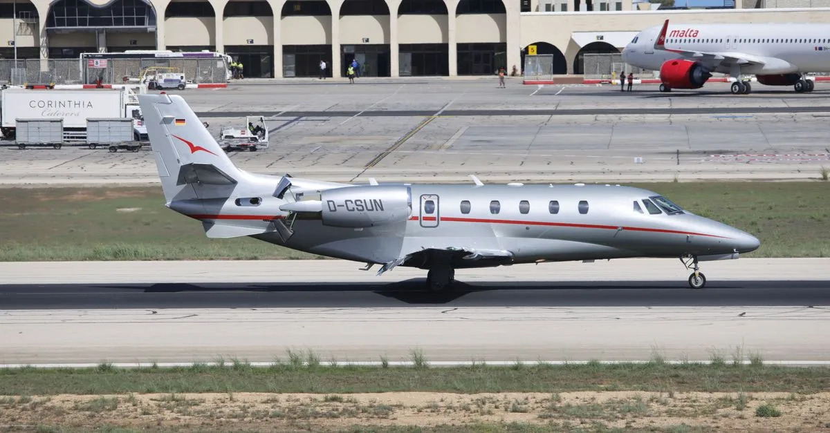 Private jet on runway at Malta's international airport under clear skies.