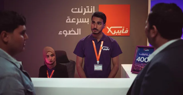 People interacting at a tech company front desk with modern design and branding.