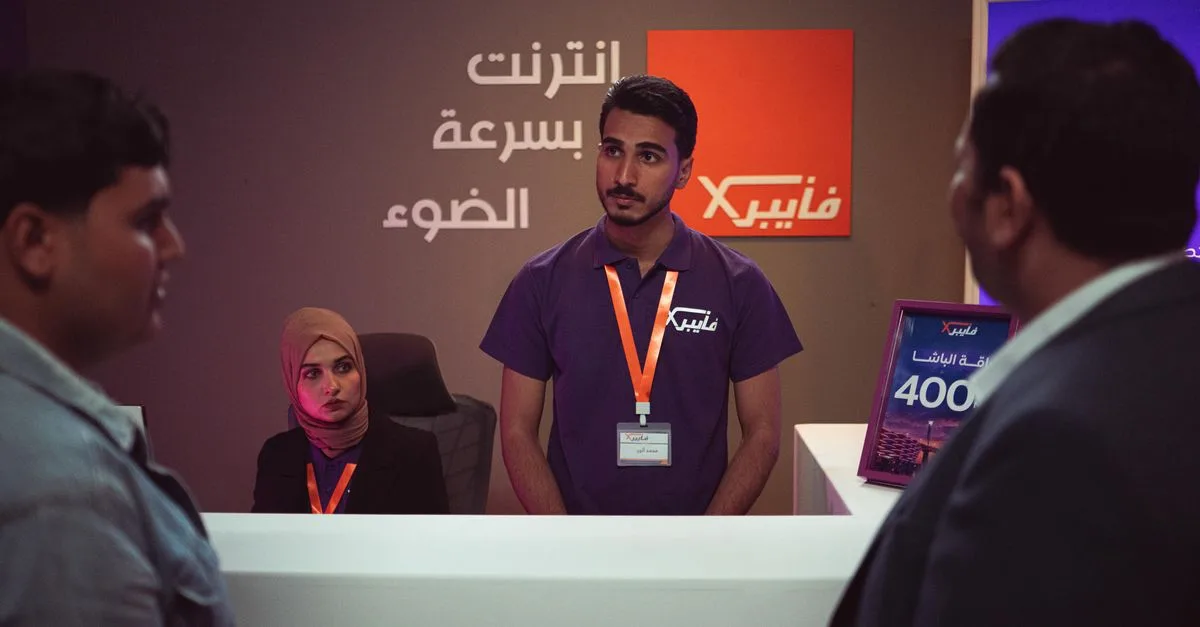 People interacting at a tech company front desk with modern design and branding.