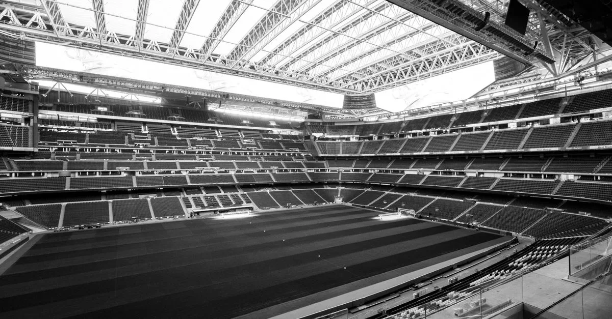 Black and white photograph of a large stadium with retractable roof in Madrid, Spain.
