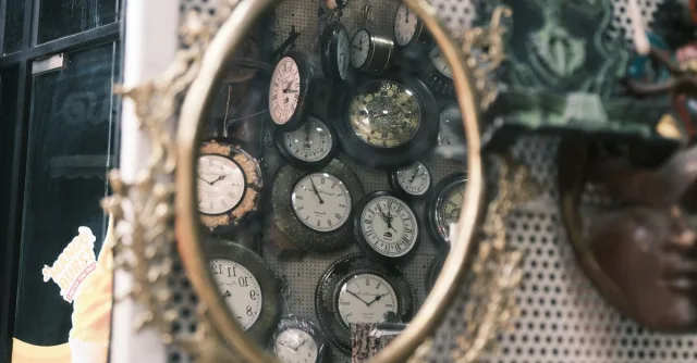 A collection of vintage clocks reflected in an ornate antique mirror in Bengaluru, India.