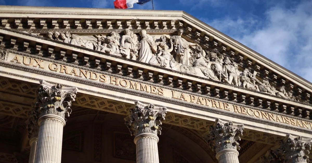 Historic Pantheon in Paris featuring detailed facade with French flag under a blue sky. Cultural landmark.
