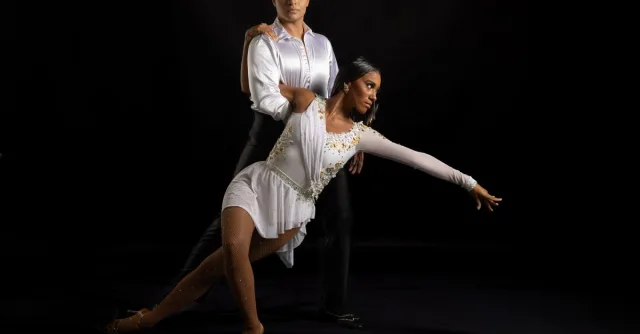 A poised couple performing ballroom dance with elegance in a studio setting.