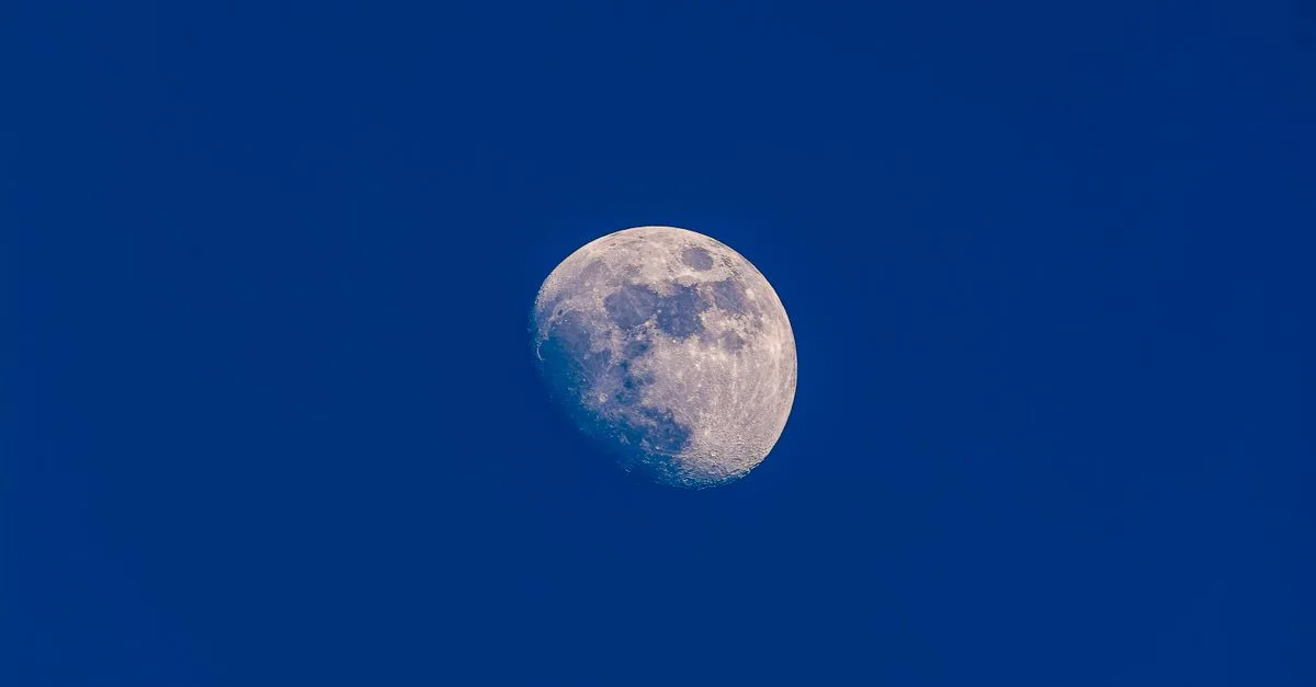 A clear view of the waxing gibbous moon set against a vibrant blue sky, showcasing lunar details.