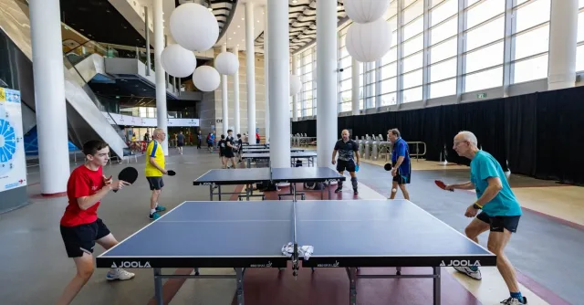 Exciting table tennis game in a modern indoor venue. Players engaged under bright lighting and stylish decor.
