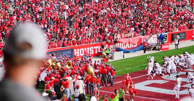 Cheerful fans at a college football game in Houston, TX, showcasing school spirit and vibrant energy.