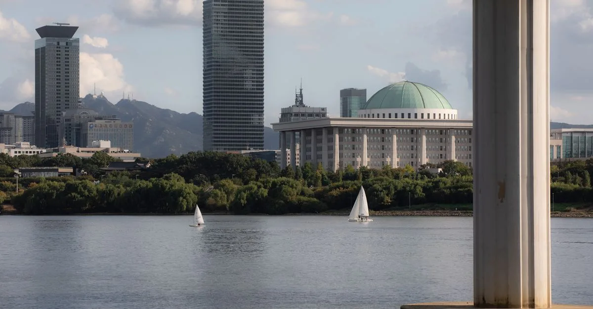 Tranquil scene featuring sailboats and city's iconic architecture along Han River.