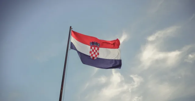 The Croatian flag blowing in the wind against a clear blue sky, symbolizing national pride.
