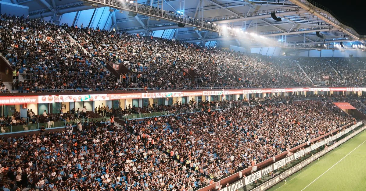 Crowd fills a vibrant soccer stadium at night with bright lights and a lively atmosphere.