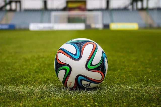 An illuminated football stadium pitch during an evening match.