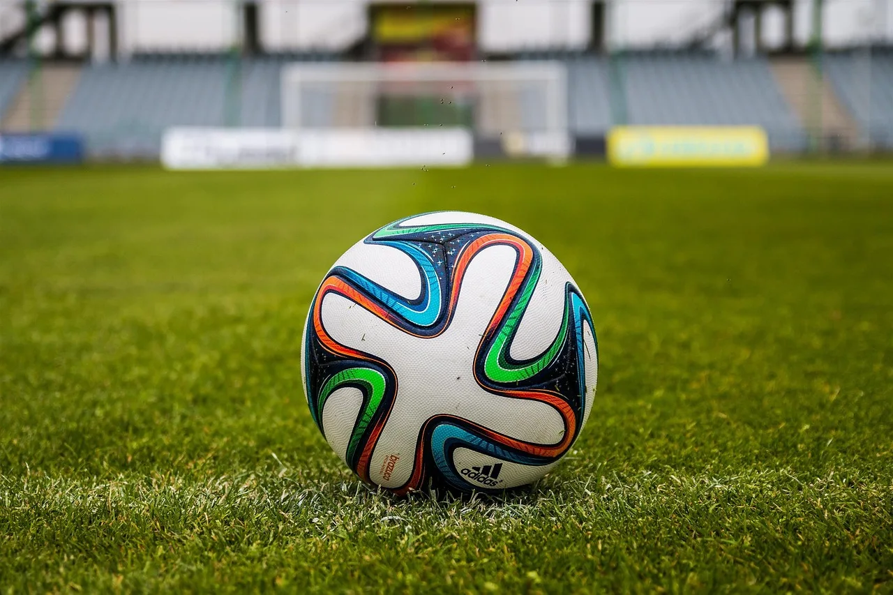 An illuminated football stadium pitch during an evening match.
