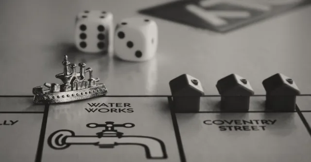 Detailed monochrome close-up of Monopoly game board with ship token, dice, and houses.