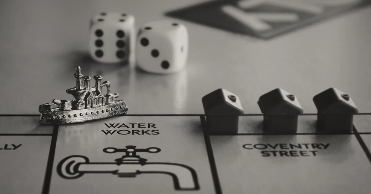 Detailed monochrome close-up of Monopoly game board with ship token, dice, and houses.