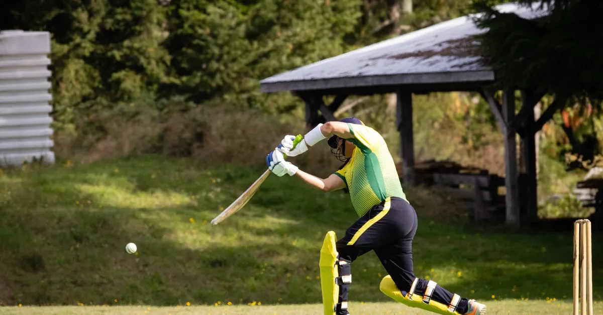 Cricketer playing a dynamic shot in a vibrant outdoor setting during a match.