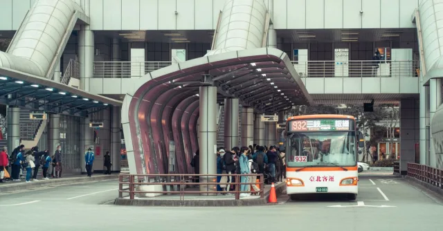 Public transport bus picking up commuters at a modern urban terminal with architectural features.