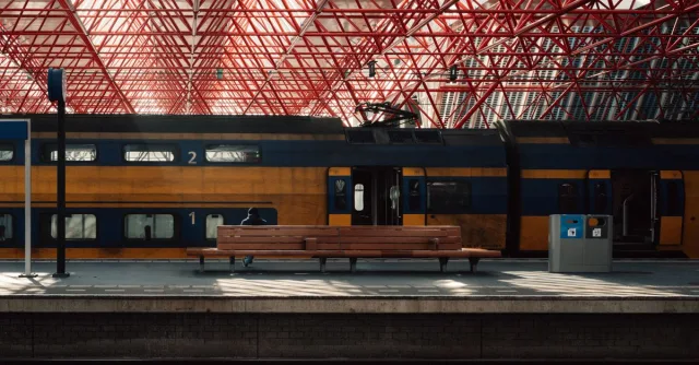 A modern train station platform in Almere with unique red steel architecture and public transport.