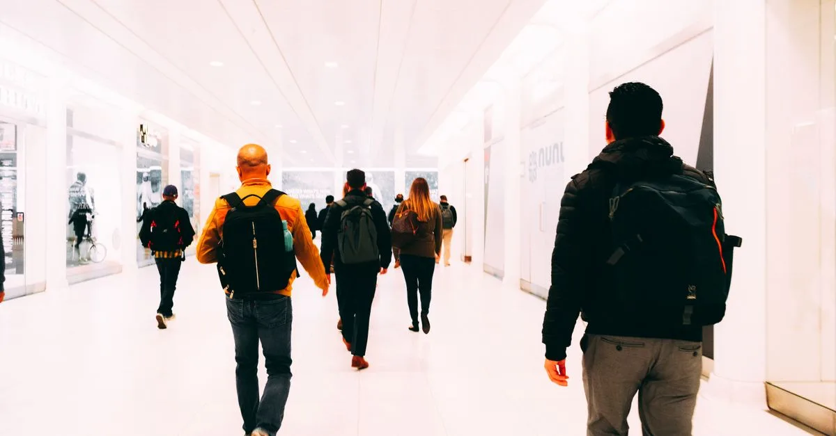 Group of travelers walking through a bright, modern airport terminal carrying backpacks.