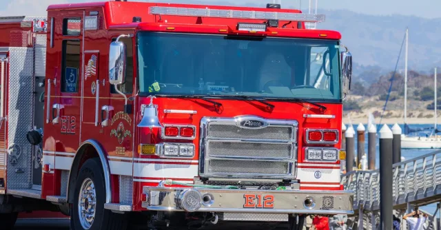 A vibrant red firetruck parked near the waterfront in Monterey, capturing an emergency vehicle in a scenic location.
