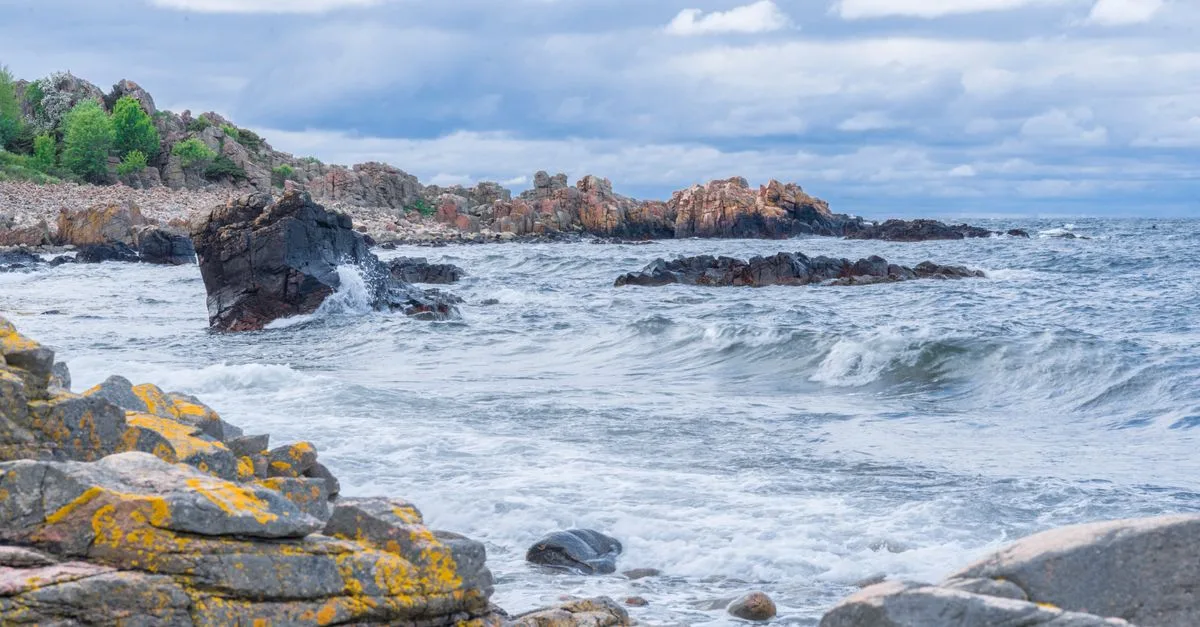 Dramatic scene of rocky coastline with waves crashing in Skåne län, Sweden.