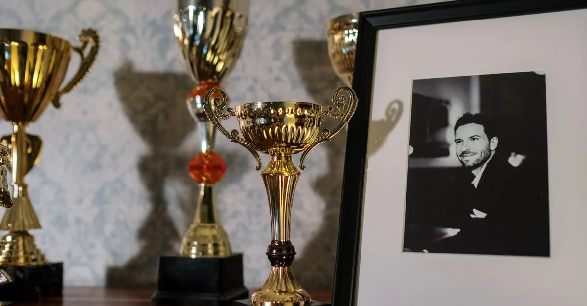 A collection of trophies with a framed black and white portrait on a shelf.