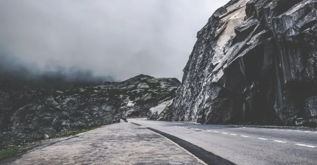 Empty mountain road through foggy Swiss landscapes, perfect for travel and adventure themes.