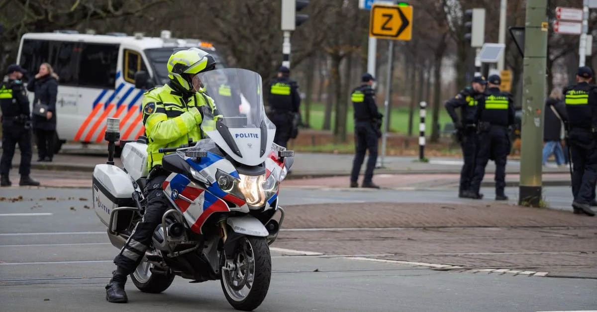 Officer on police motorcycle leading street surveillance, flanked by fellow officers.