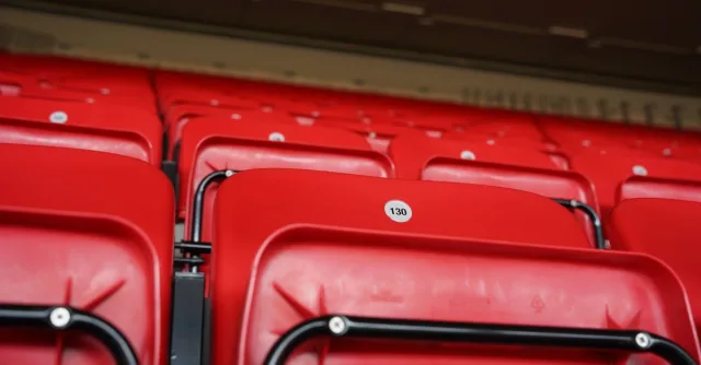 Close-up of numbered red stadium seats in an empty arena, highlighting seats at a famous stadium.