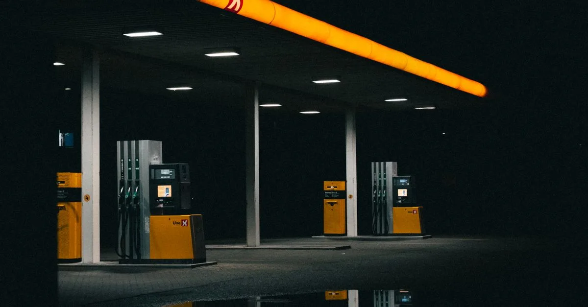 A moody nighttime photo of an empty gas station with orange lights.