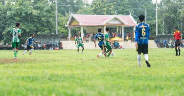 Amateur soccer players compete on a rainy day at a local field.