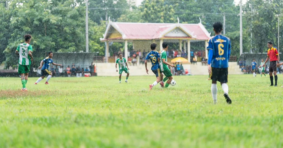 Amateur soccer players compete on a rainy day at a local field.