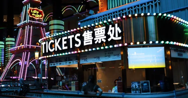 Illuminated ticket booth with vibrant neon lights at night, featuring colorful signage.