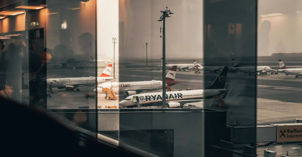 Airplanes at a bustling airport with reflections of interiors in the window panes.