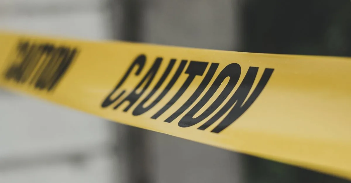 Close-up image of yellow caution tape with blurred background, emphasizing warning and safety.