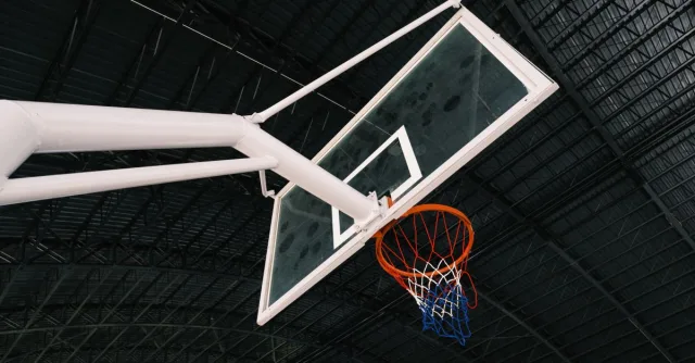 Close-up of an indoor basketball hoop and backboard in an empty sports hall.