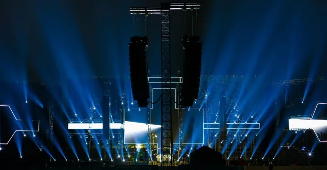 Nighttime concert stage illuminated by vibrant blue lights.