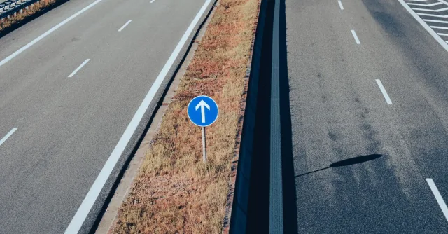 Aerial view of an empty highway highlighting a traffic sign with an arrow, emphasizing direction and transportation infrastructure.