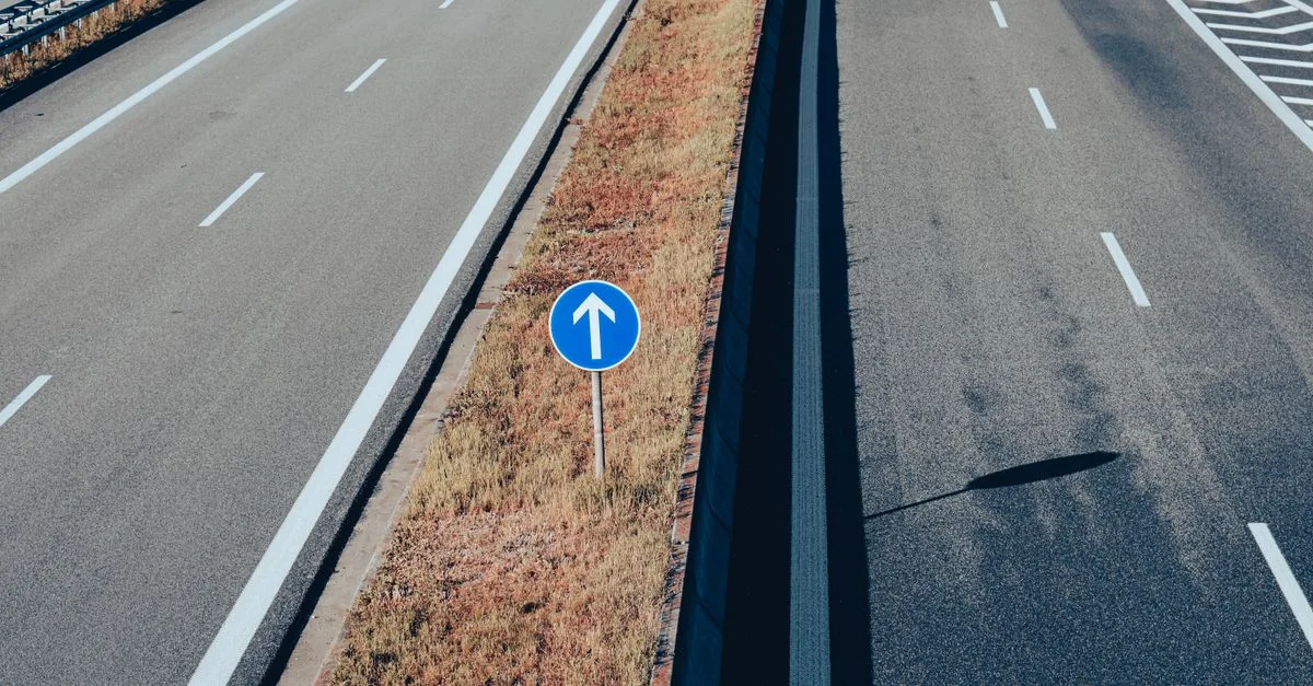Aerial view of an empty highway highlighting a traffic sign with an arrow, emphasizing direction and transportation infrastructure.