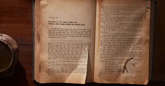 A vintage open book with text in Vietnamese on a wooden table, showcasing old literature.
