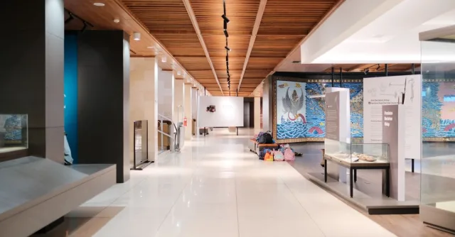 Bright museum hallway with exhibits and empty walkways, showcasing modern design.