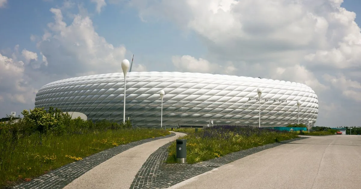 A striking modern stadium design under a cloudy summer sky, showcasing urban architectural beauty.