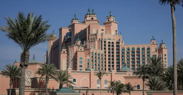 Elegant view of the Atlantis Hotel in Dubai with palm trees under a clear blue sky.
