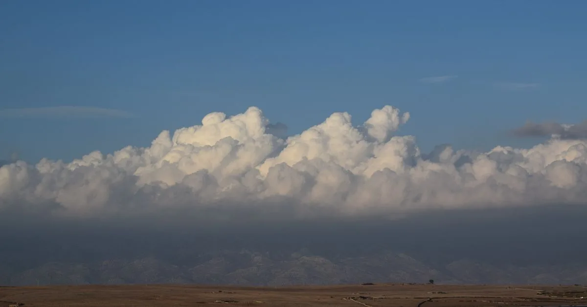 Beautiful cumulus clouds hovering over a tranquil mountain landscape and serene lake.