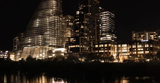 Illuminated skyscrapers reflecting in the river at night in downtown Austin, Texas.