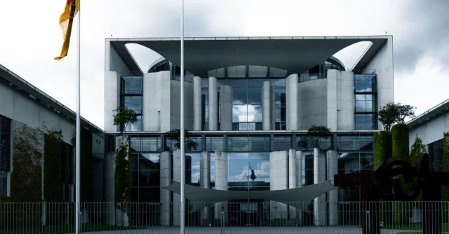 Contemporary architecture of a government building with German flag under cloudy skies.