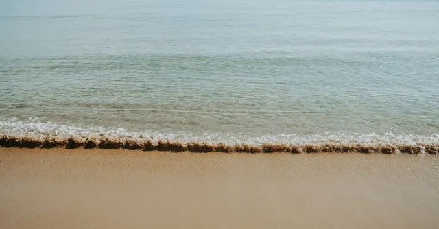 Calm and serene beach with gentle waves lapping on the sandy shore. Perfect for relaxation.