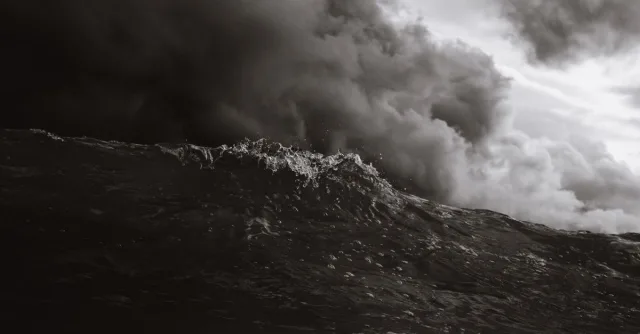 Powerful ocean wave with storm clouds in monochrome, capturing nature's intensity.