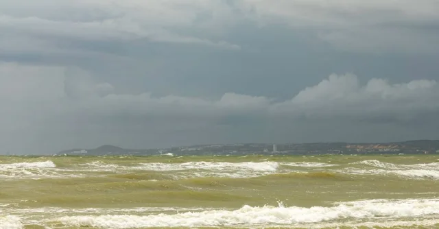 A captivating view of the ocean under a stormy sky. Turbulent waves and dark clouds create a dramatic seascape.