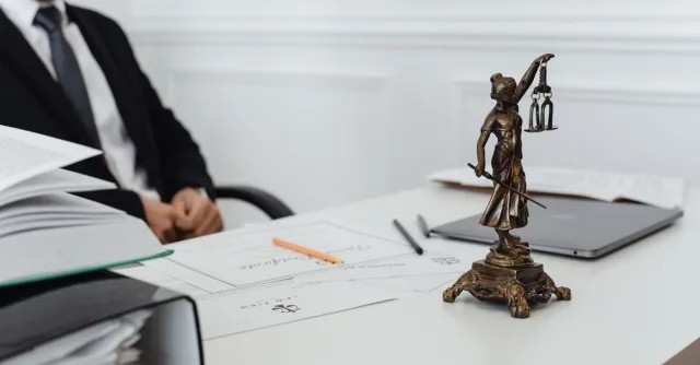 A legal professional's workspace featuring Lady Justice statue, documents, and a laptop.